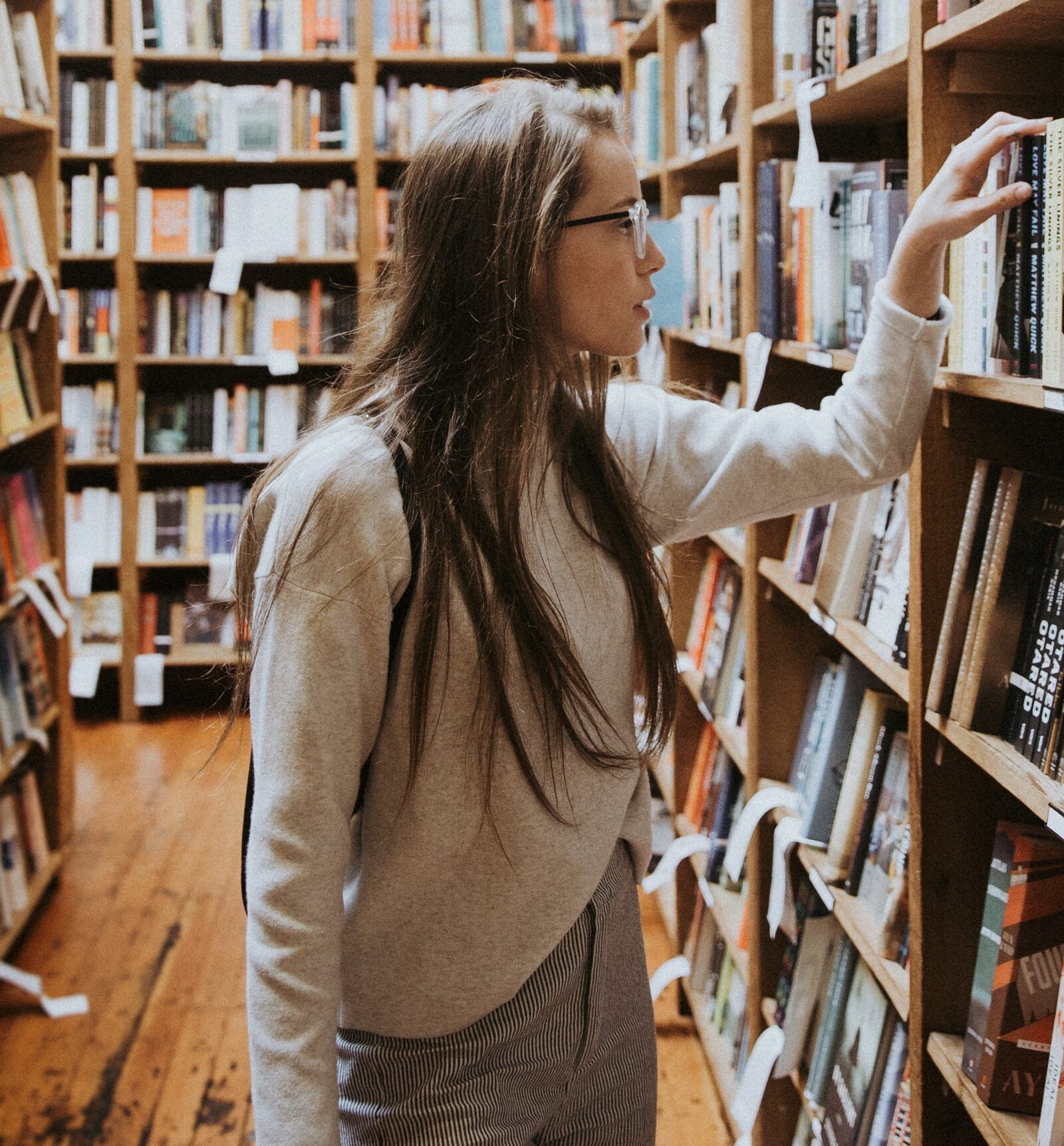 An instructor browsing shelves of books in a library